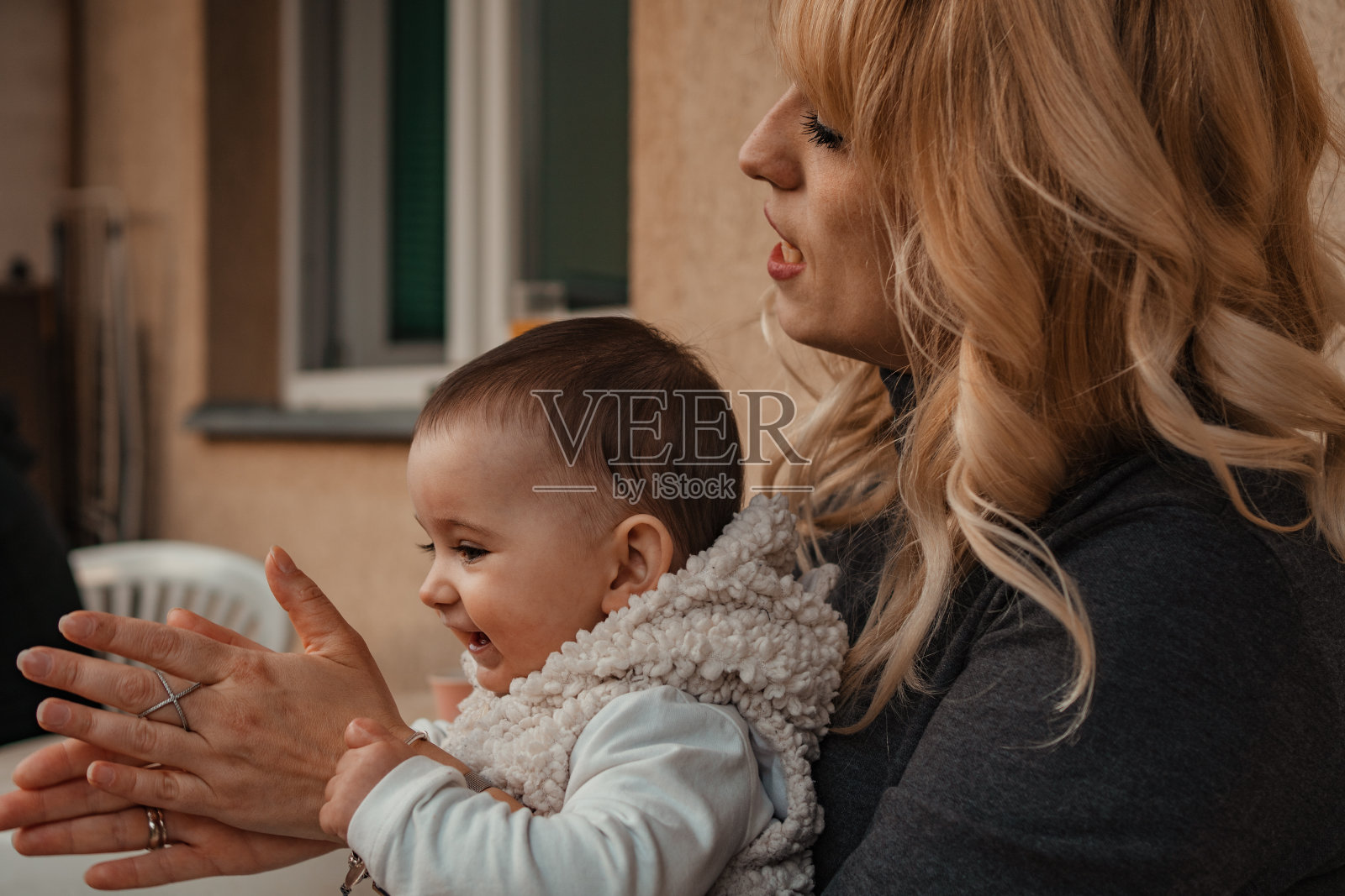 一个可爱的小女孩在妈妈的怀里玩得很开心照片摄影图片