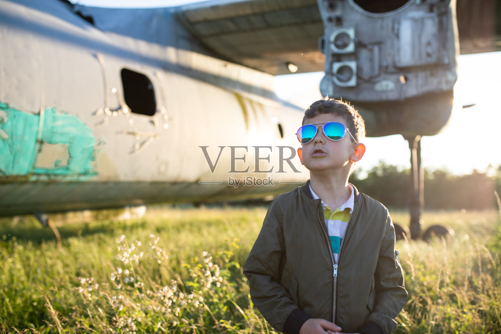 一个可爱的小男孩站在一架失事的飞机旁眺望远方照片摄影图片