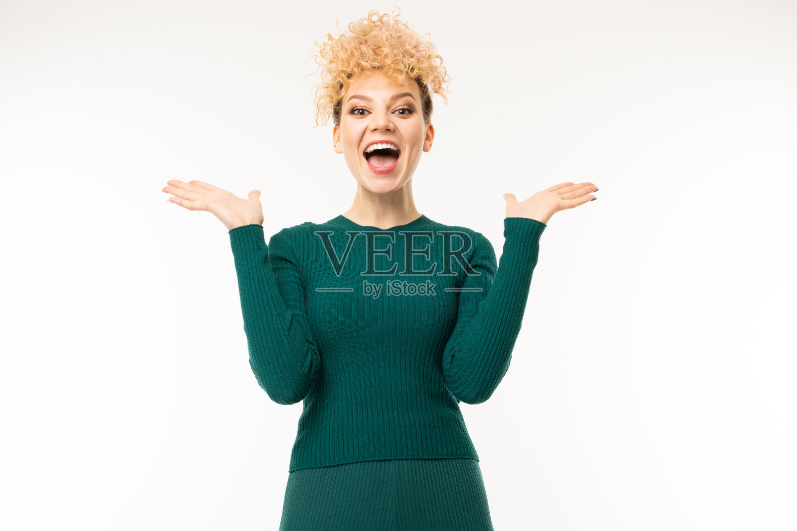 在一个白色的画室背景上，一个穿着绿色衣服的金发卷毛女孩的肖像照片摄影图片