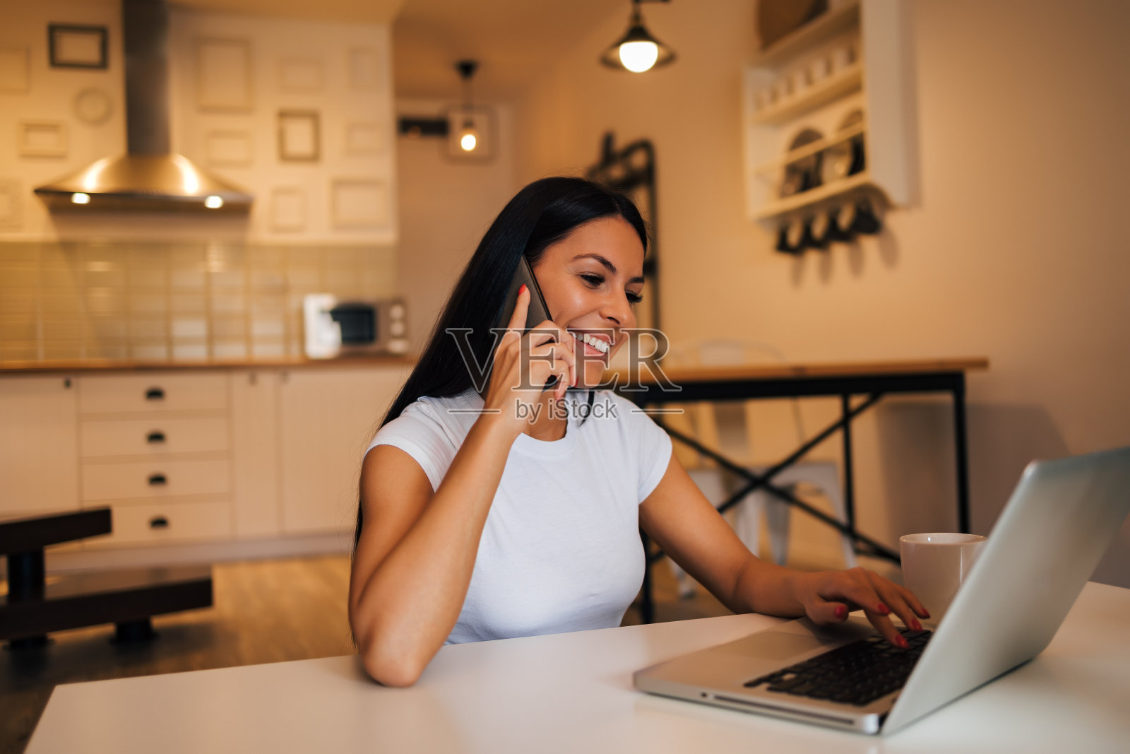 在家里用笔记本电脑和智能手机工作的漂亮女人，肖像。照片摄影图片