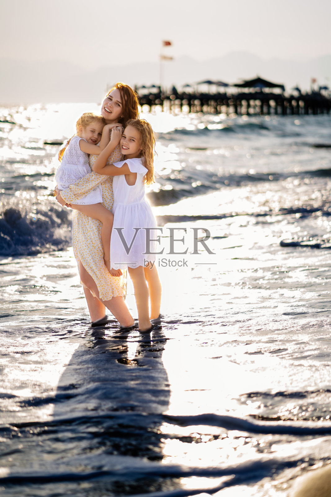 在大风天气里，妈妈和孩子在波涛汹涌的海滩上散步。幸福的家庭照片摄影图片