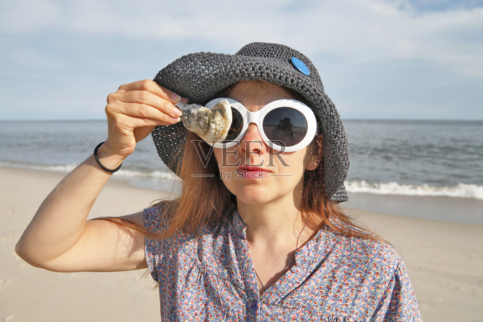 一个女人在海滩上拿着牡蛎壳。照片摄影图片