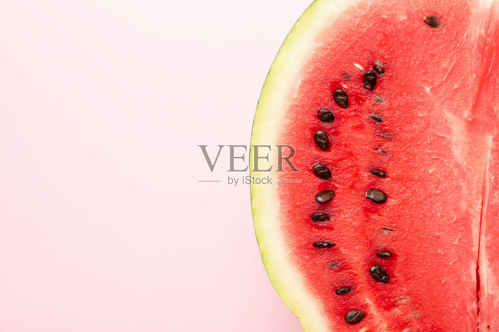 一半的新鲜西瓜在粉红色的背景上。夏天的水果照片摄影图片