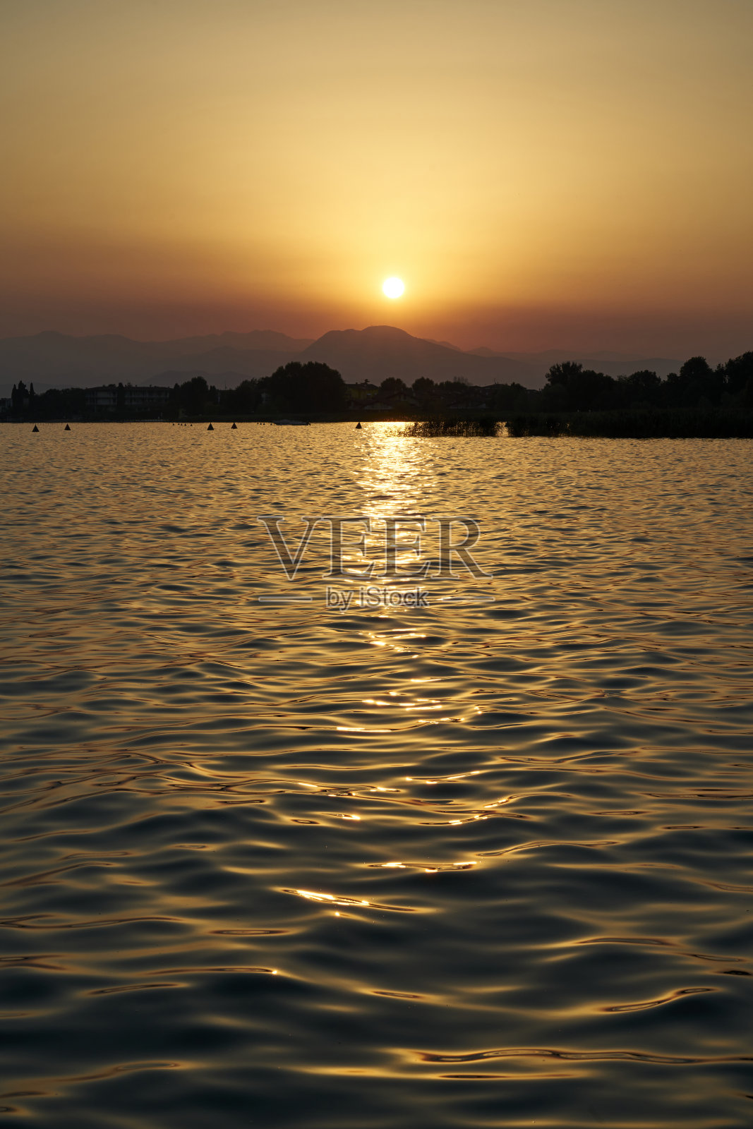 湖面上宁静的晨光，山上初升的太阳。照片摄影图片