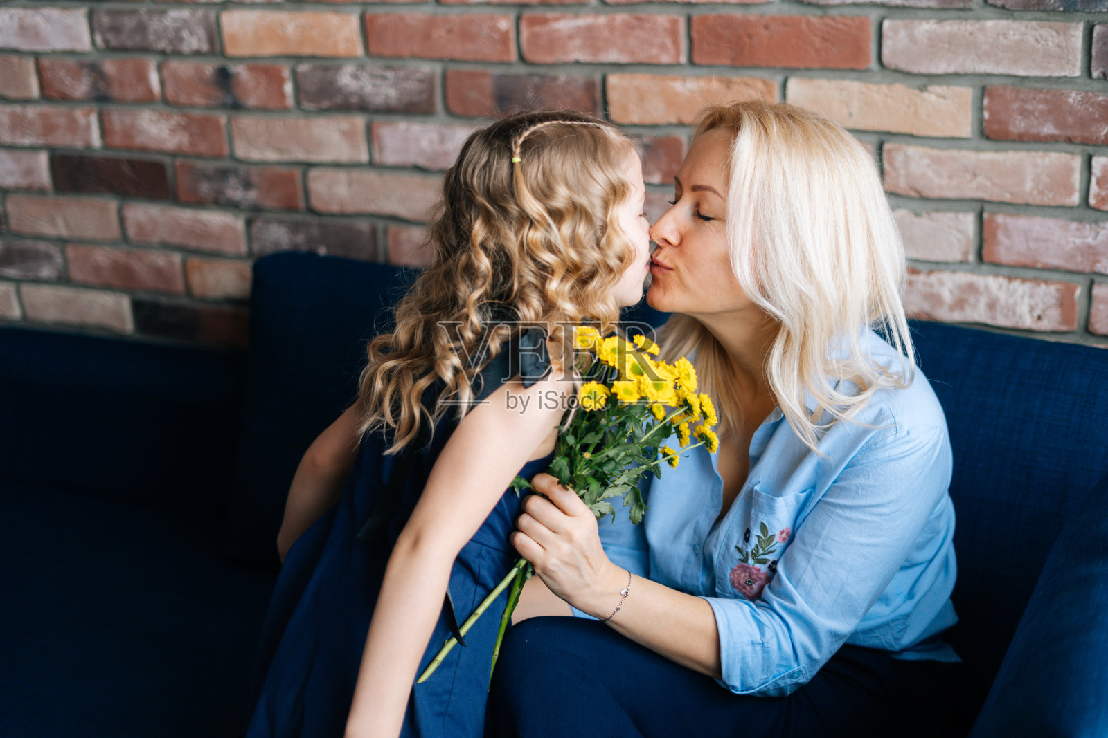 女儿和妈妈在家里接吻，女孩给妈妈一束花照片摄影图片