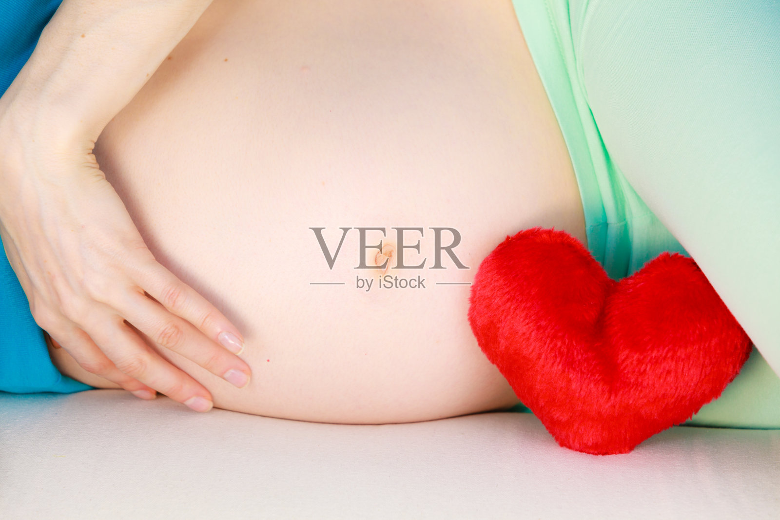 一名孕妇躺在沙发上，抚摸着自己的肚子照片摄影图片