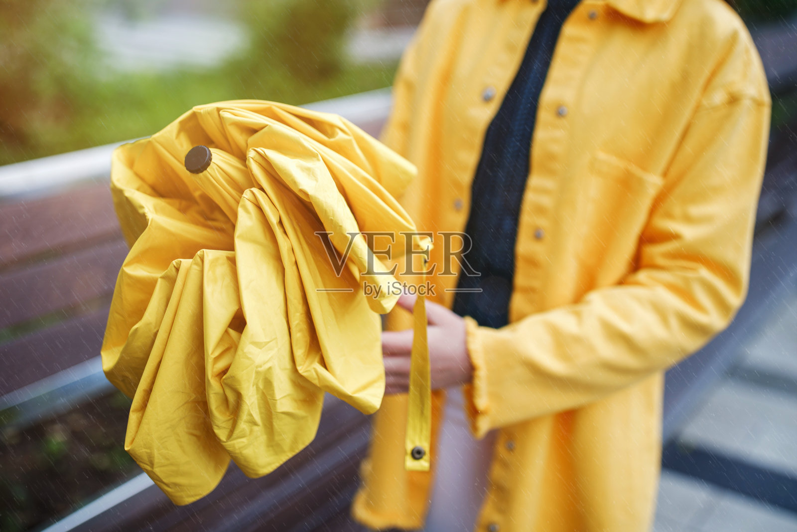 一个年轻漂亮的少女走在城市的雨天。这个女孩穿着彩色的衣服和胶靴照片摄影图片