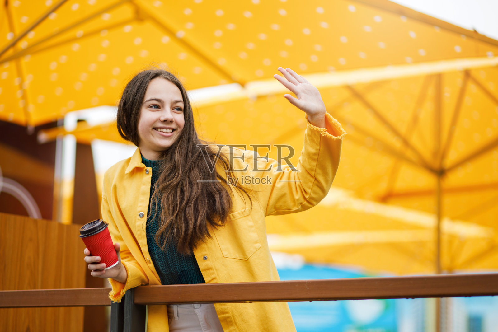 一个年轻漂亮的少女走在城市的雨天。这个女孩穿着彩色的衣服和胶靴照片摄影图片