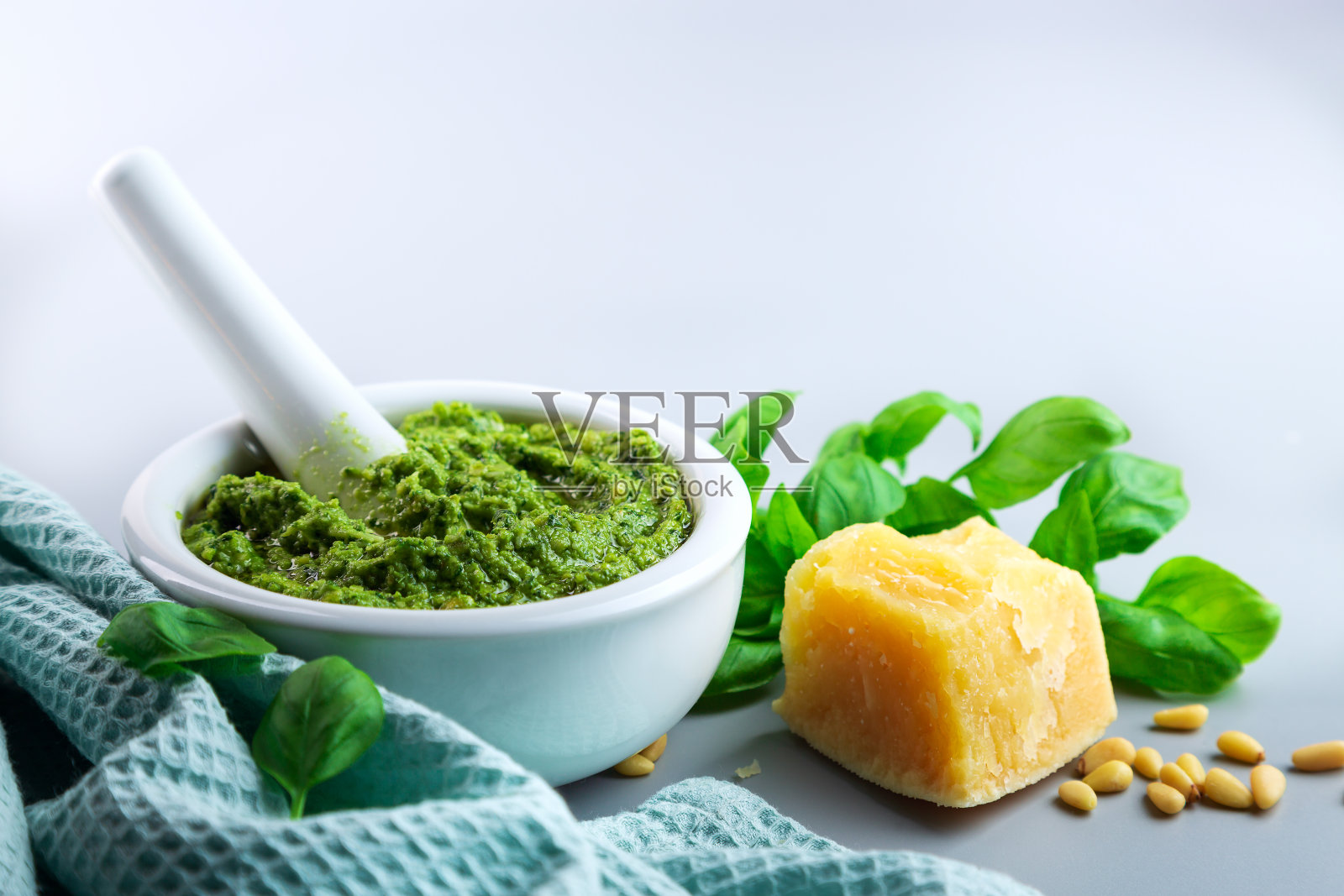 灰色的桌子上放着自制的罗勒香蒜酱。副本的空间。照片摄影图片