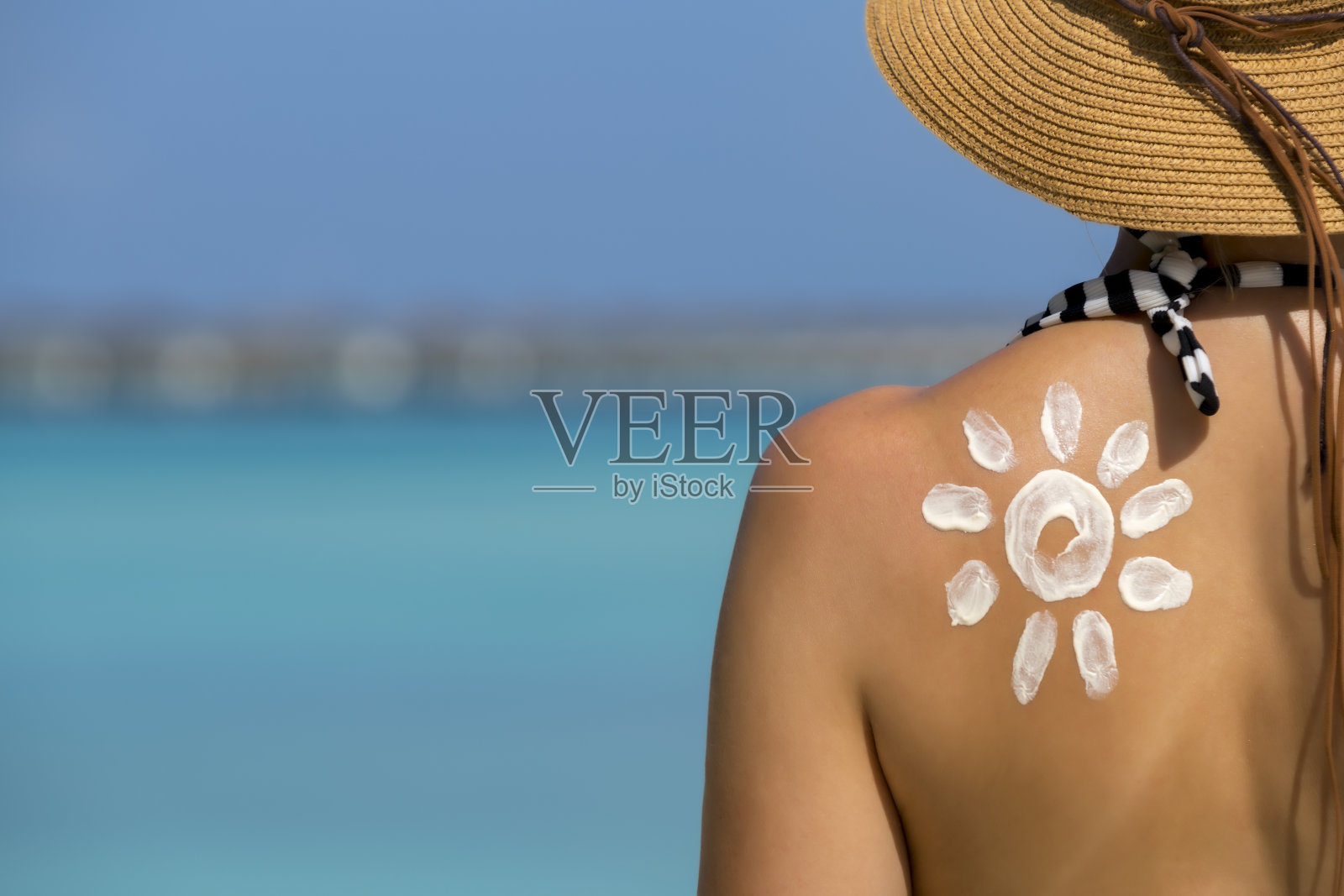 在海滩上涂着太阳形状的防晒霜的女人照片摄影图片