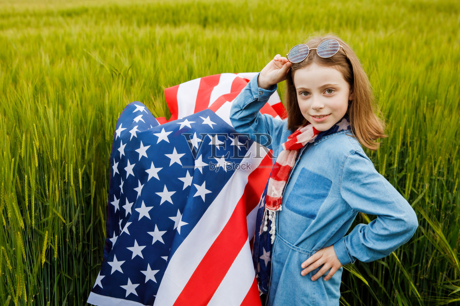 十多岁的小女孩在战场上举着美国国旗。照片摄影图片