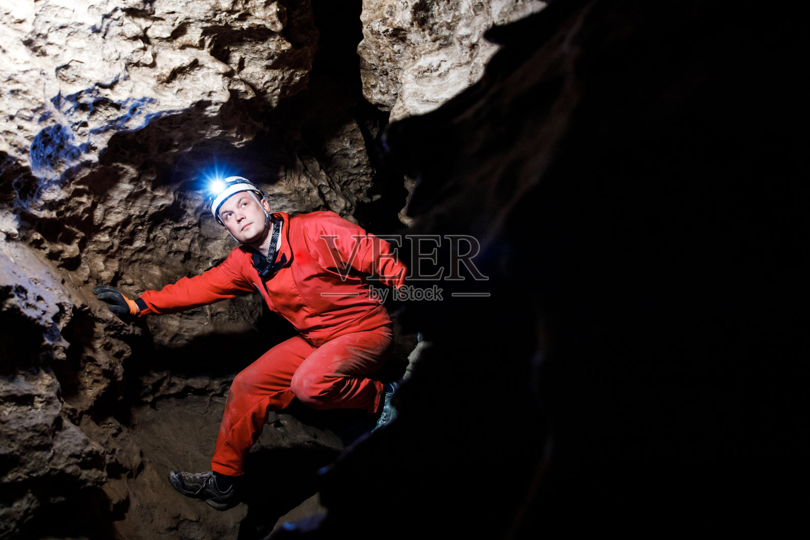 在地下，人们带着灯光前照灯在黑暗的洞穴中行走和探索。神秘的幽深黑暗，探险家在岩壁上发现神秘的穆迪隧道。照片摄影图片
