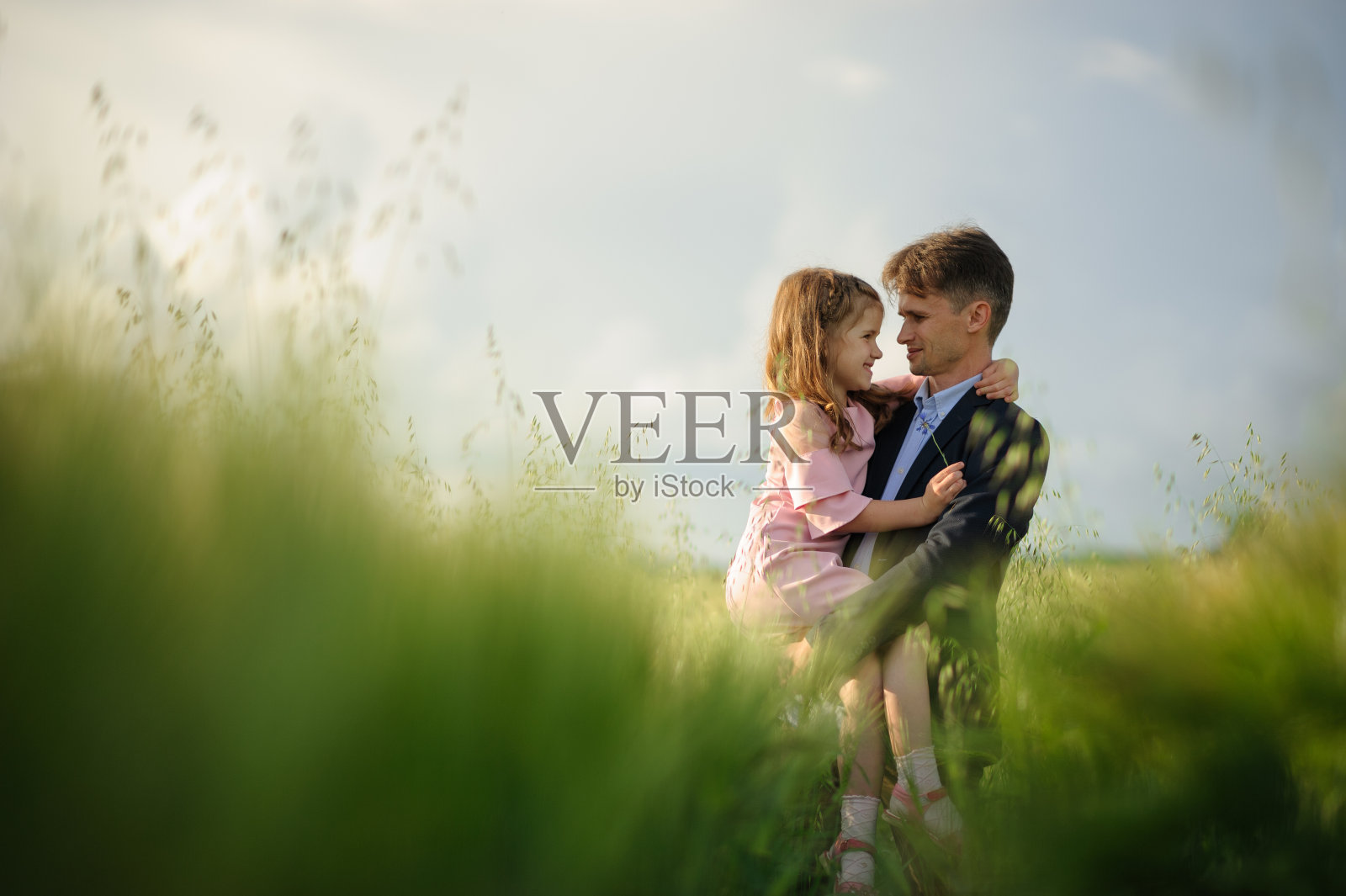 父亲和女儿在绿色的麦田里。照片摄影图片