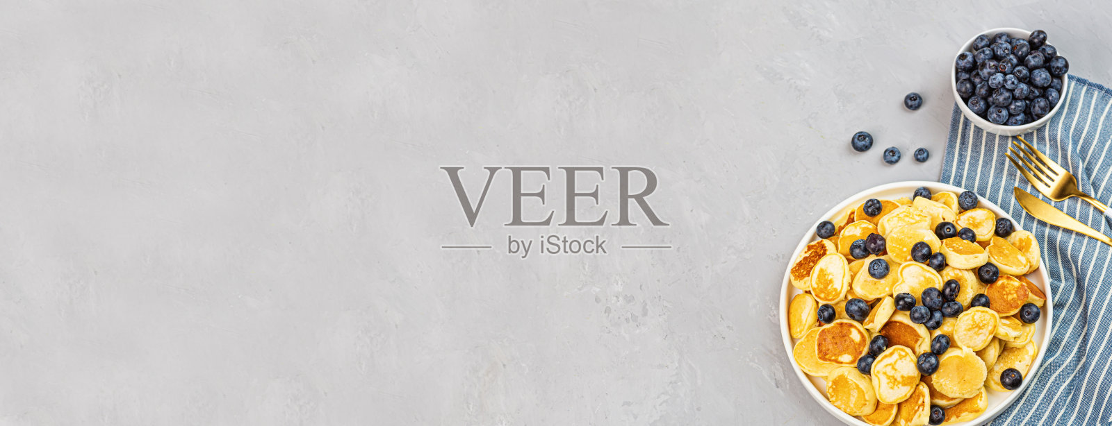 时髦的家庭早餐，小煎饼和蓝莓在灰色的混凝土背景。网页横幅。平铺，俯视图，头顶，模型，模板，复制空间。从上面的观点照片摄影图片