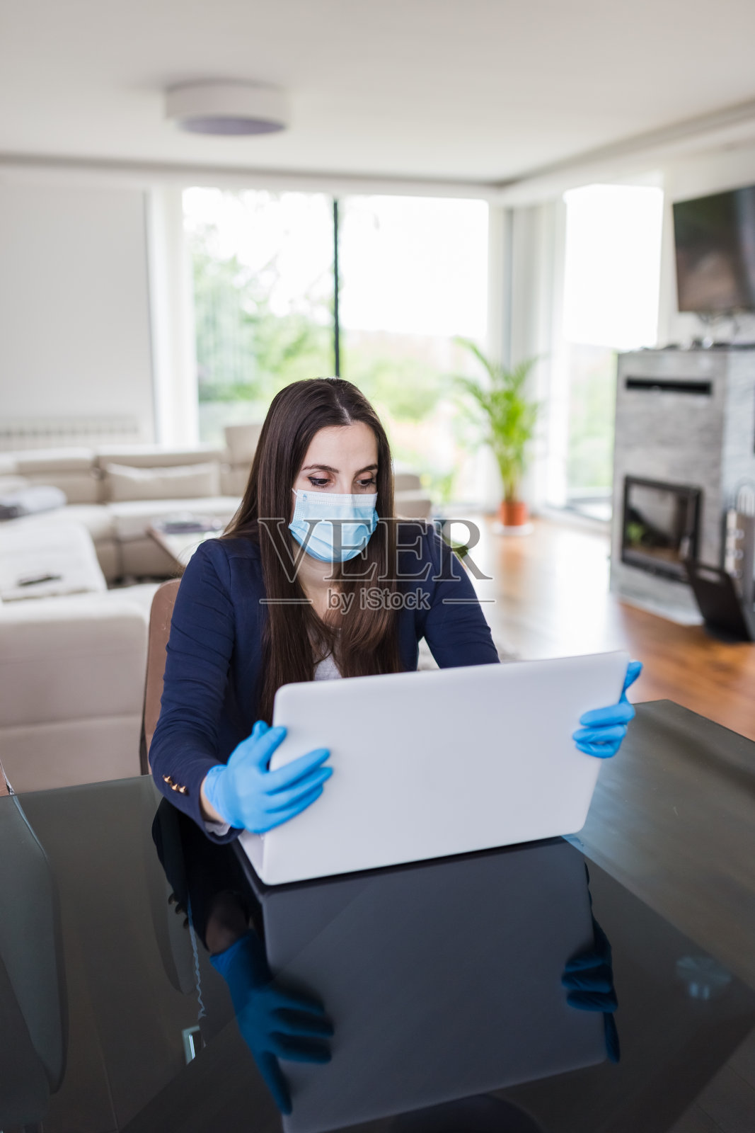 年轻女商人戴着外科口罩和手套在家在线工作，covid-19隔离概念。照片摄影图片