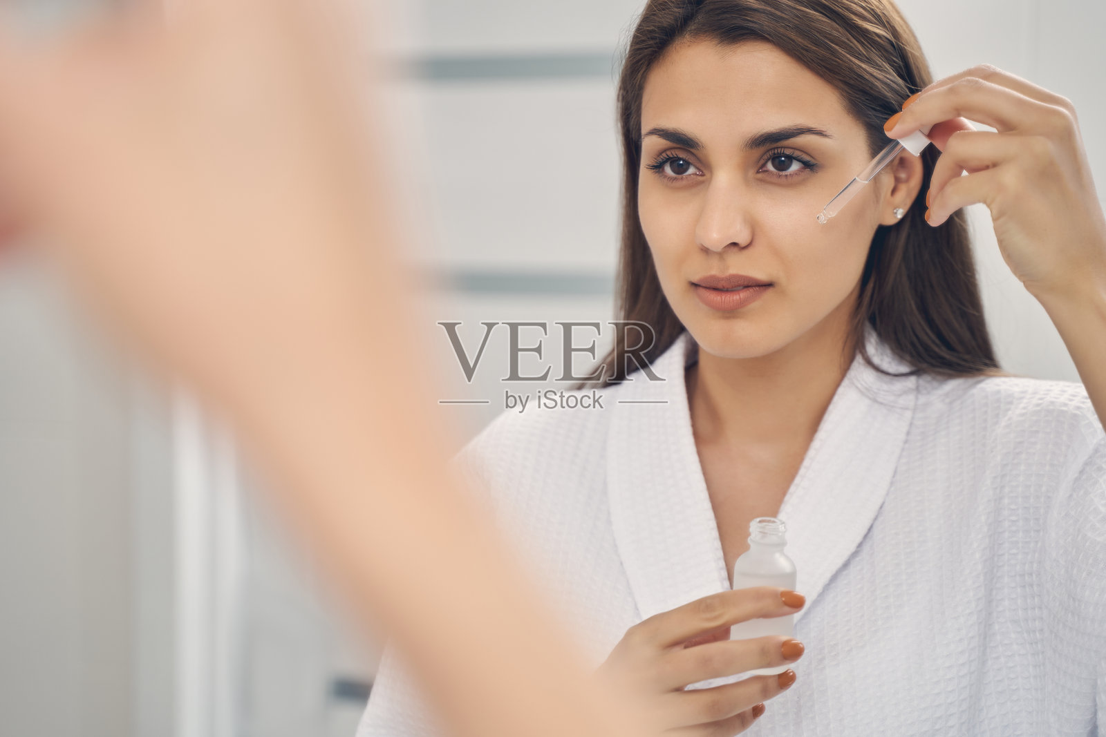 美丽的年轻女子在脸颊上涂抹维生素血清照片摄影图片