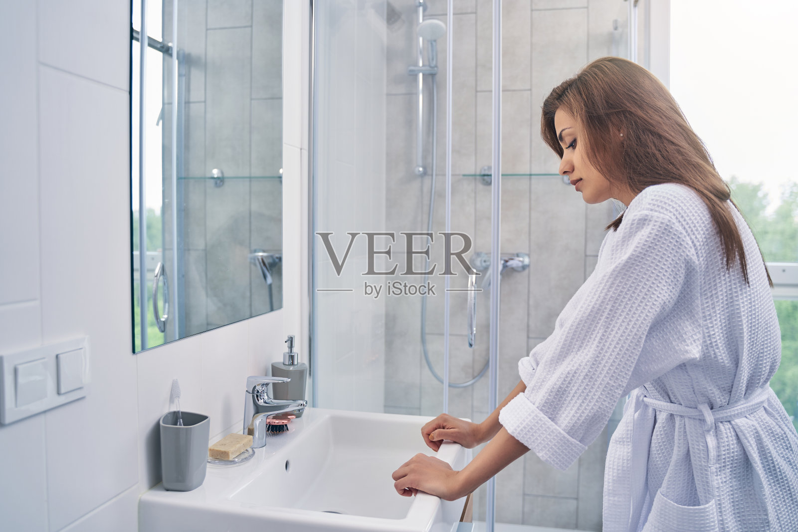 漂亮的年轻女子站在浴室的水槽边照片摄影图片