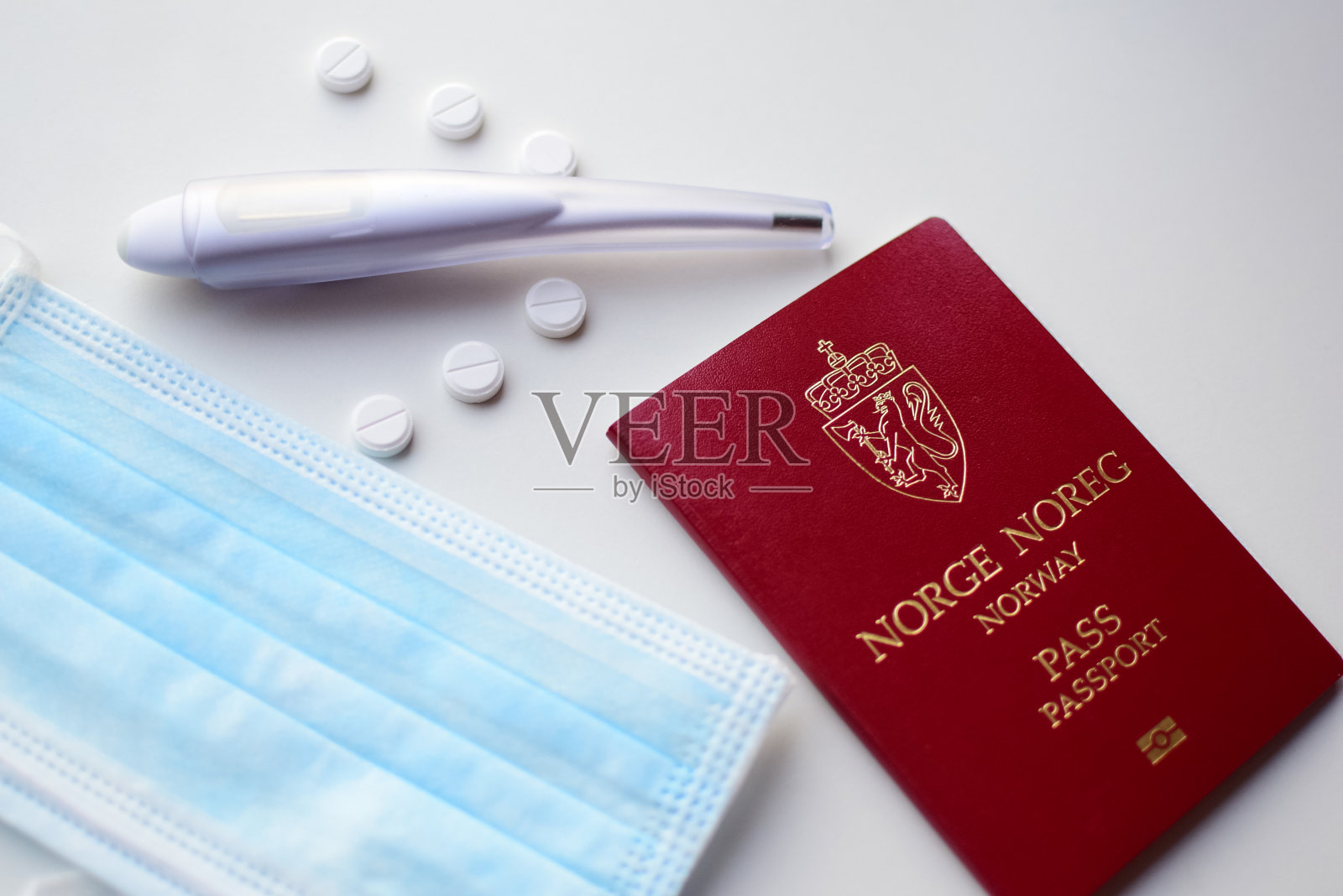 白色背景上有挪威护照、医用口罩、机票、体温计和药片、飞机。照片摄影图片
