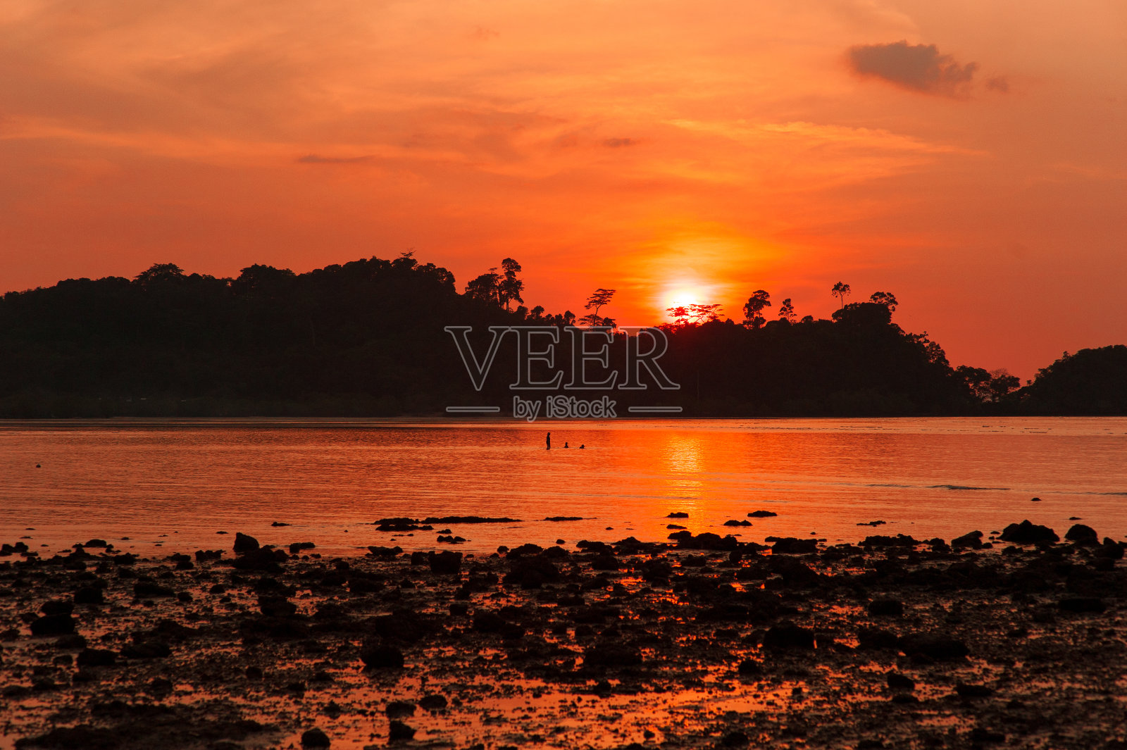 金色的落日映入大海，一个小岛的剪影。太阳，天空，大海，海浪和沙子照片摄影图片