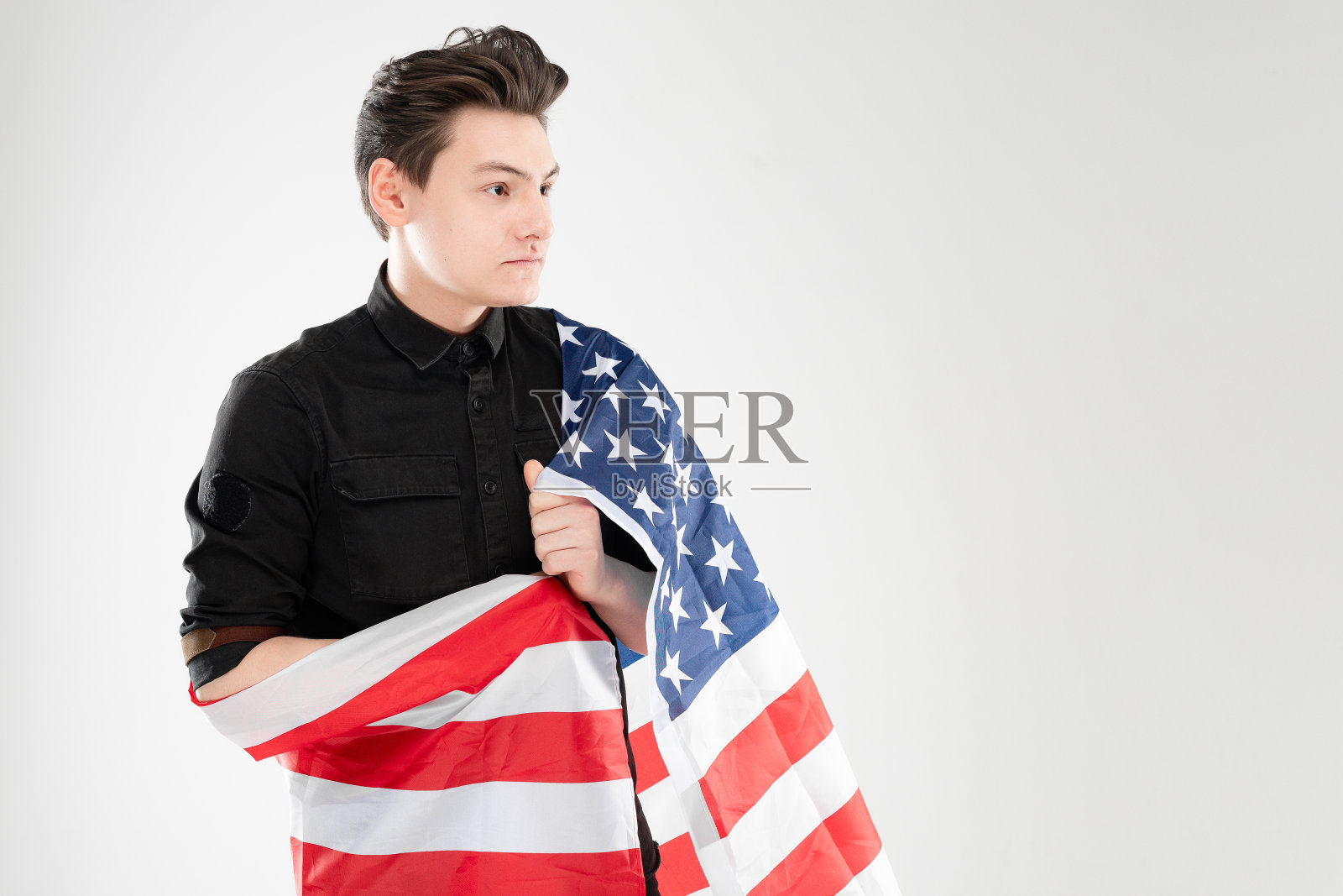 一名成年白人男子在工作室里举着美国国旗。概念与灰色背景和复制空间照片摄影图片