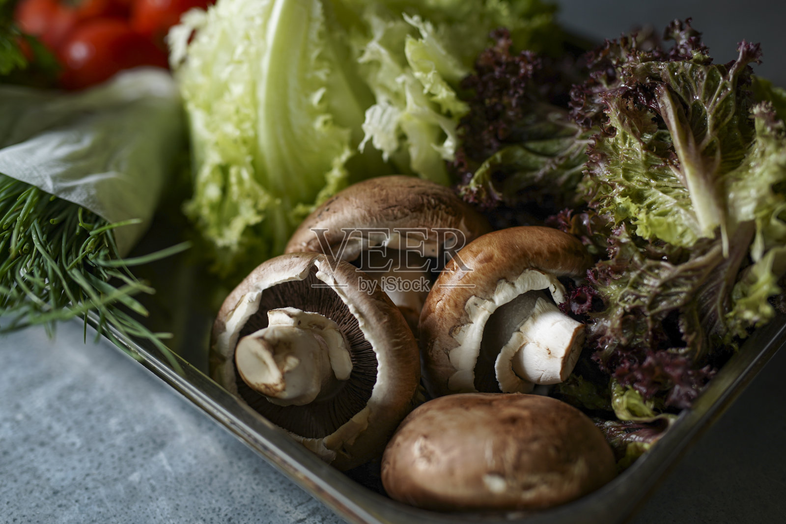 新鲜的蘑菇，生菜，欧芹，西红柿，韭菜放在托盘上。汉堡的素食成分照片摄影图片