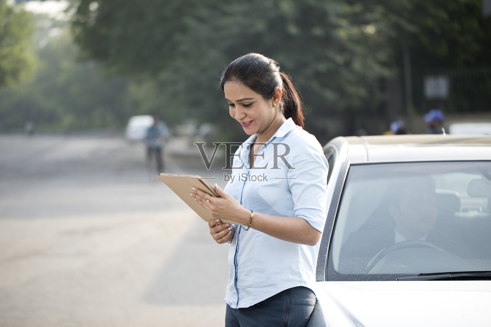 商业女性在城市里靠在汽车上使用数字平板电脑照片摄影图片