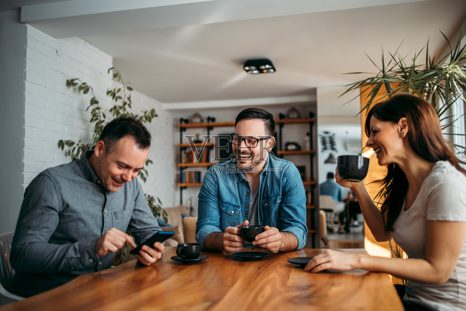 同事在现代工作场所享受咖啡休息。照片摄影图片