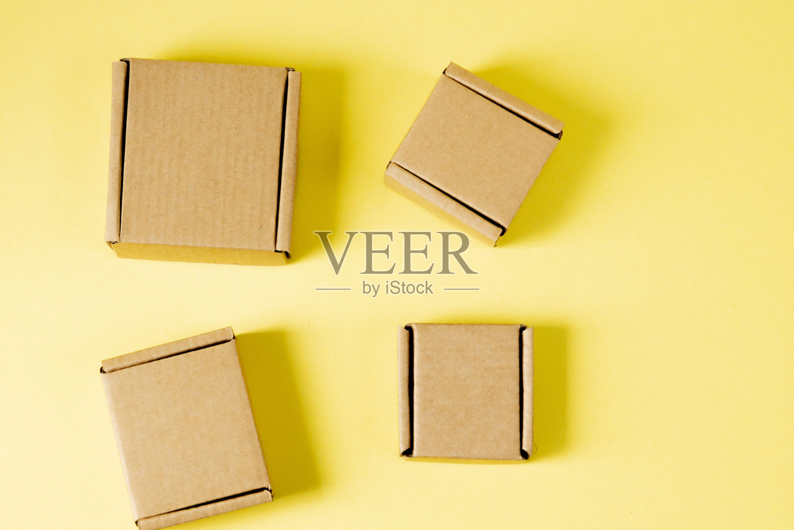 各种尺寸的纸板箱，底色为黄色。照片摄影图片