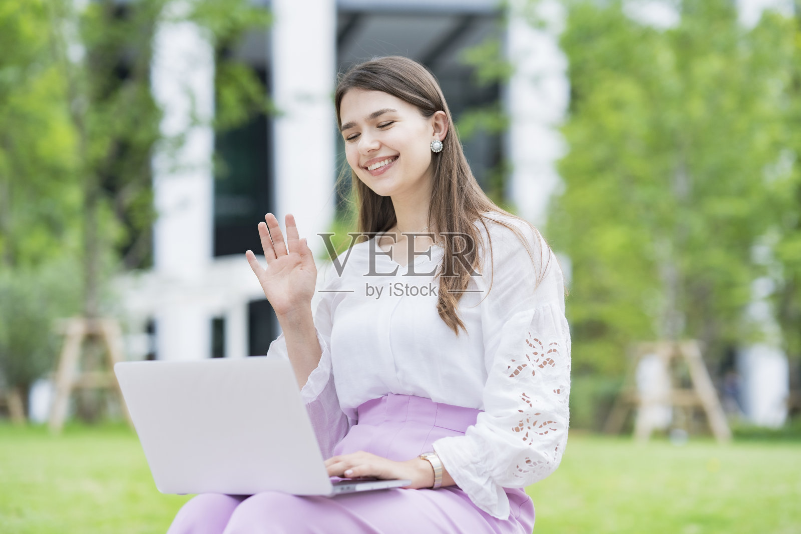 年轻女子向笔记本电脑屏幕致意照片摄影图片