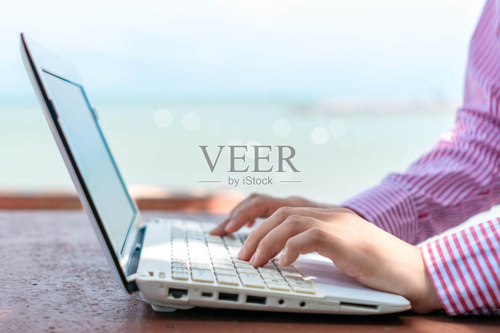 女人用手提电脑工作，在干净的自然沙滩户外背景的办公桌上学习。商业、金融、交易、股票市场和社交网络的概念。照片摄影图片