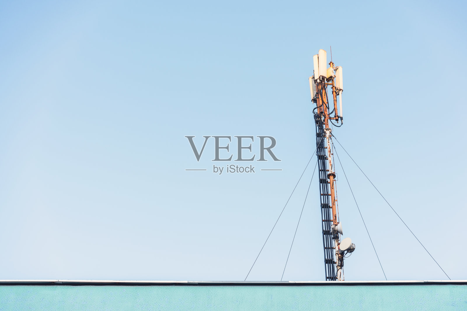 屋顶有不同天线的高通信塔，映衬着湛蓝的天空照片摄影图片