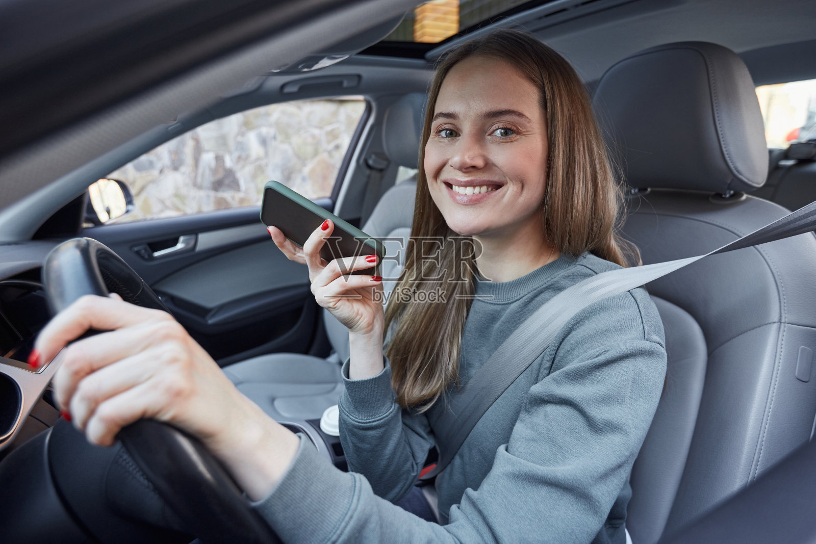 快乐的女性驾驶着一辆手持智能手机的汽车照片摄影图片