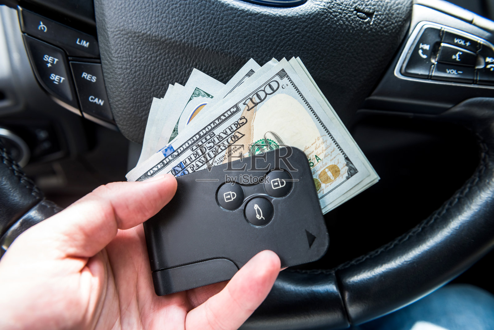 男性的手坐在车里拿着美元和车钥匙照片摄影图片