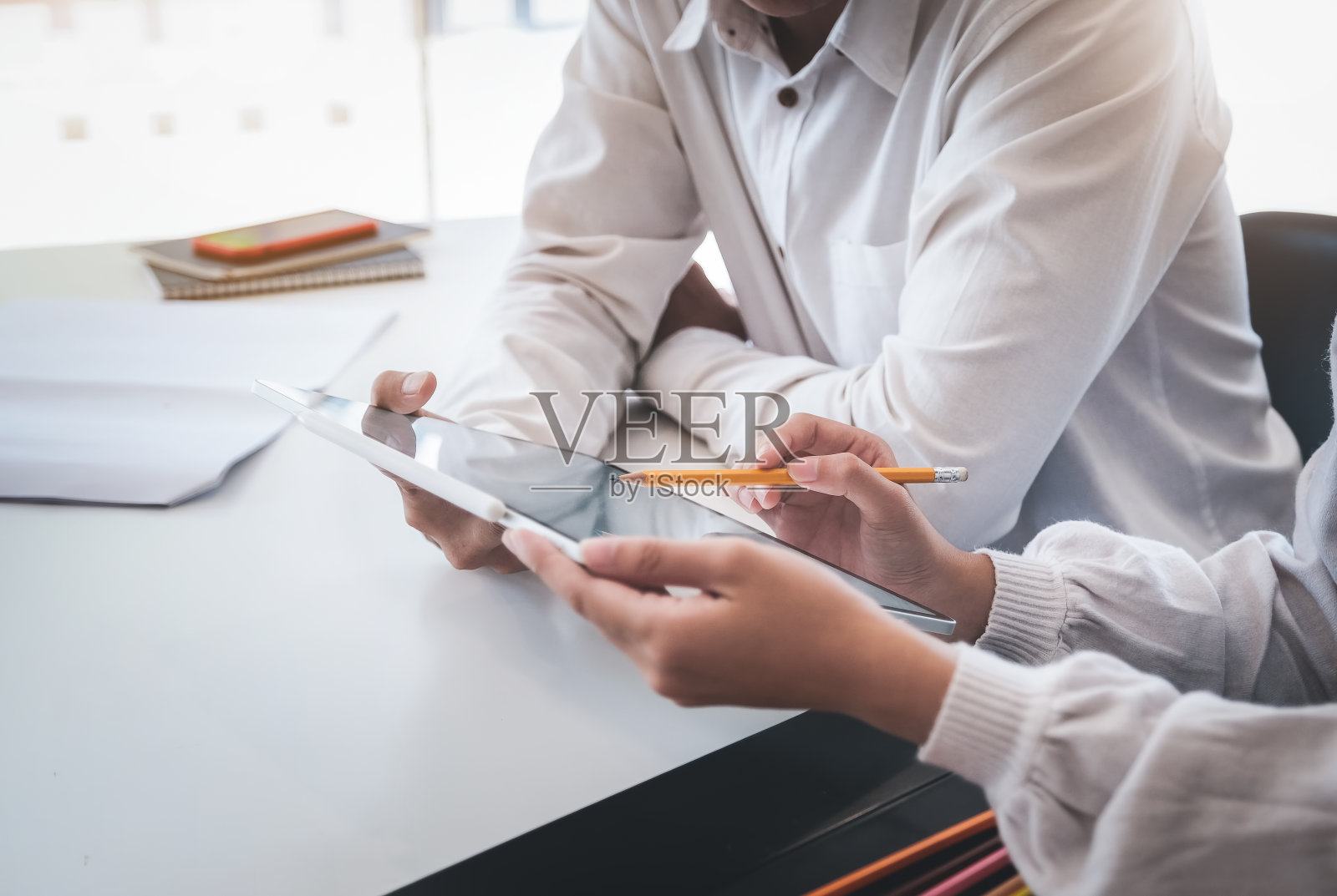 女性拿着彩色铅笔与客户交谈，用自由职业者的概念板进行设计或创作。照片摄影图片