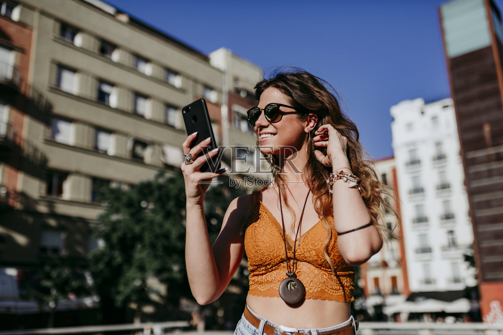 美丽的年轻白人女人走在城市的街道在一个阳光明媚的日子。用手机聊天。快乐的脸微笑着。城市的生活方式照片摄影图片