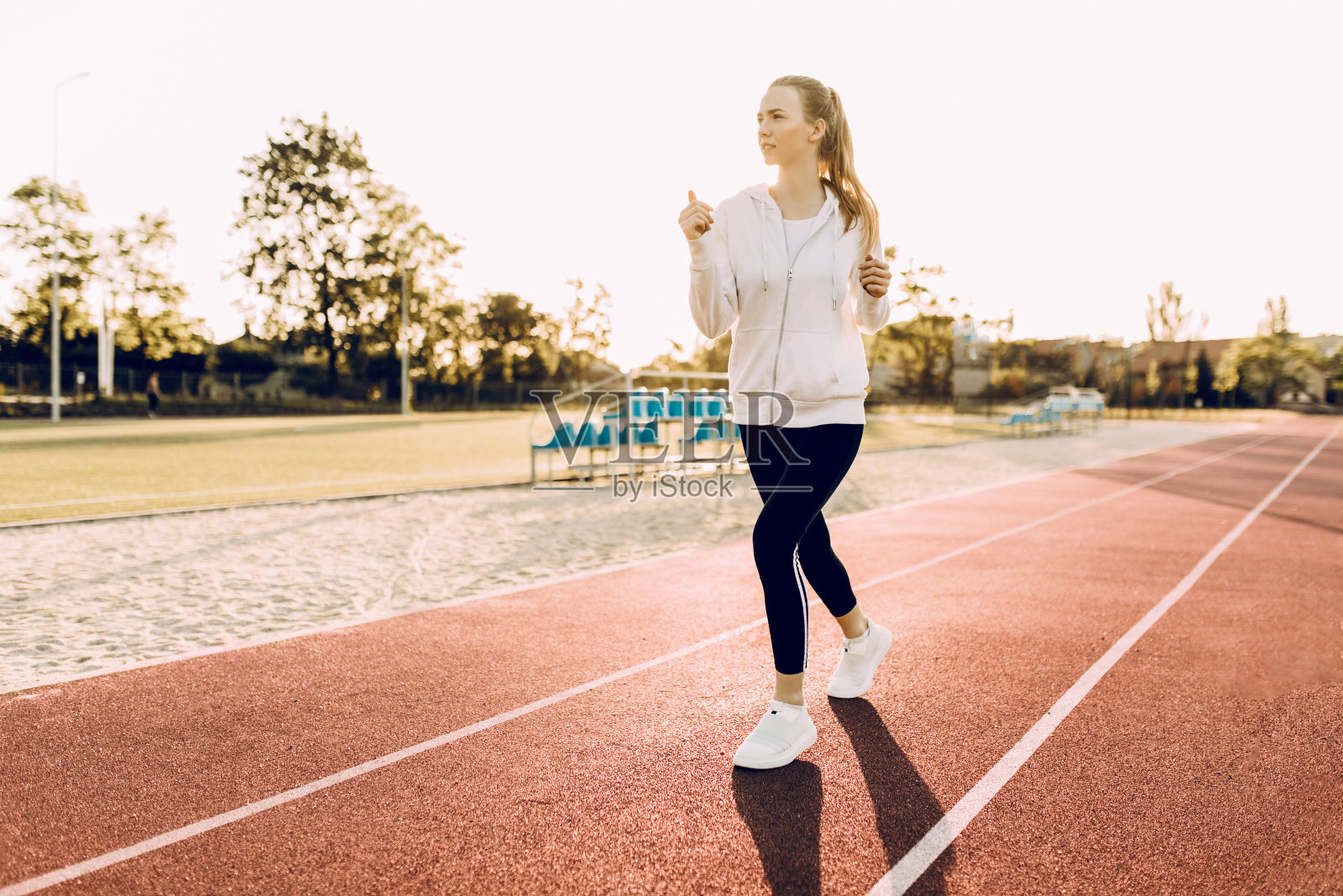 在一个阳光明媚的早晨，运动慢跑者绕着体育场跑照片摄影图片