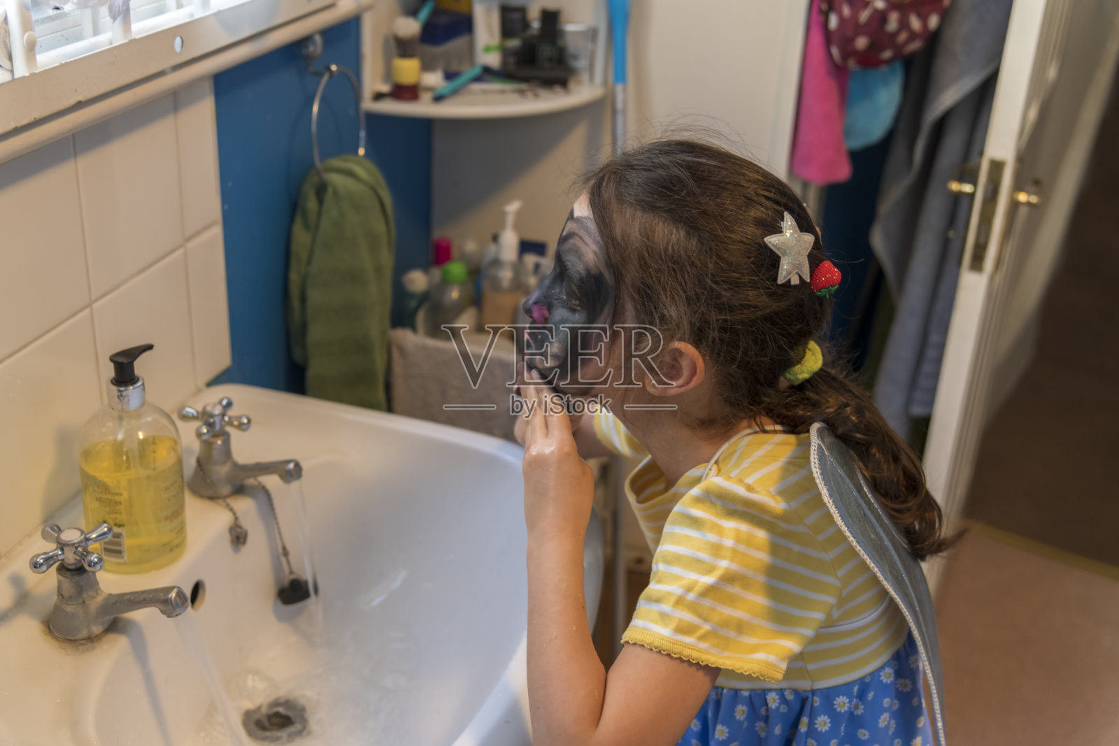 一个来自贫困家庭的年轻女孩正在用脸部彩绘来娱乐自己照片摄影图片