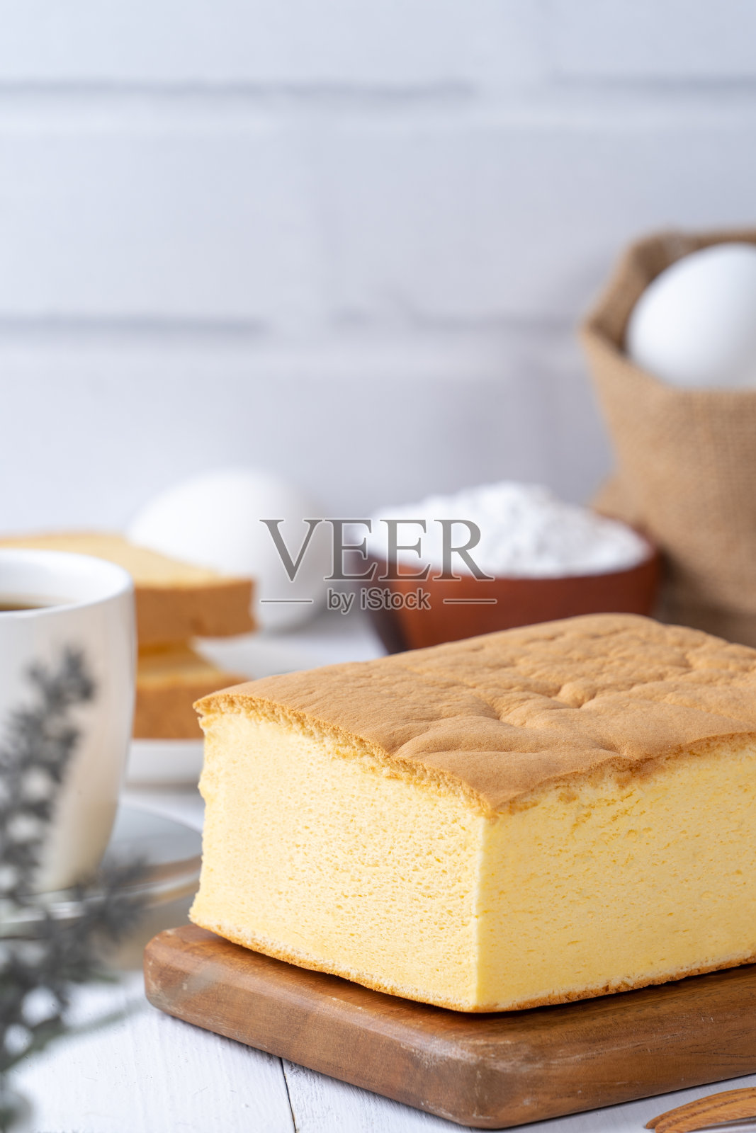 简单经典的台湾传统海绵蛋糕(台湾castella kasutera)放在一个木制托盘背景桌子上，与原料，近距离。照片摄影图片