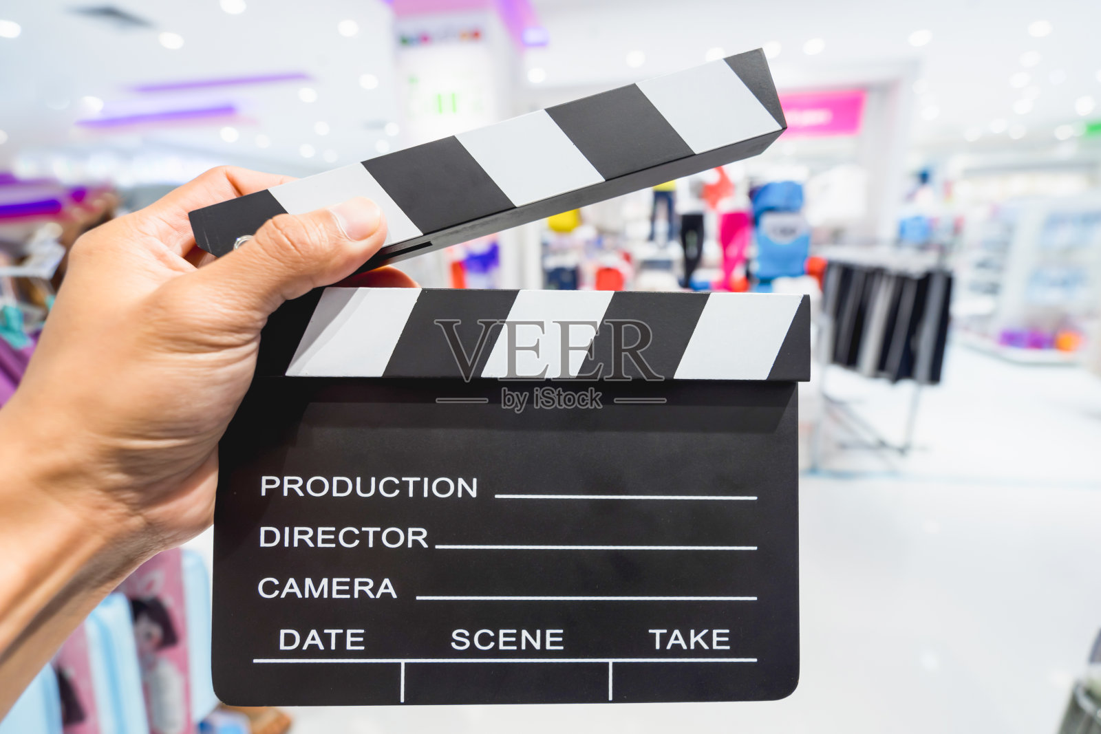 在演播室里，手持拍片板的男子。电影制作板片或板岩胶片概念。照片摄影图片