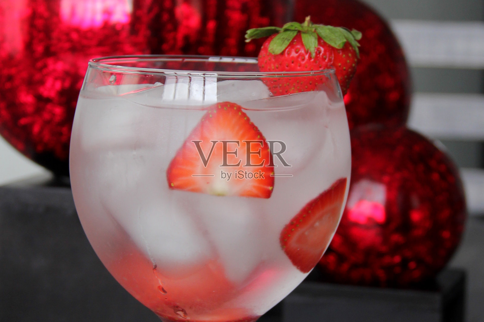 灰色的复古桌子上放着草莓杜松子酒和红色的圆球照片摄影图片