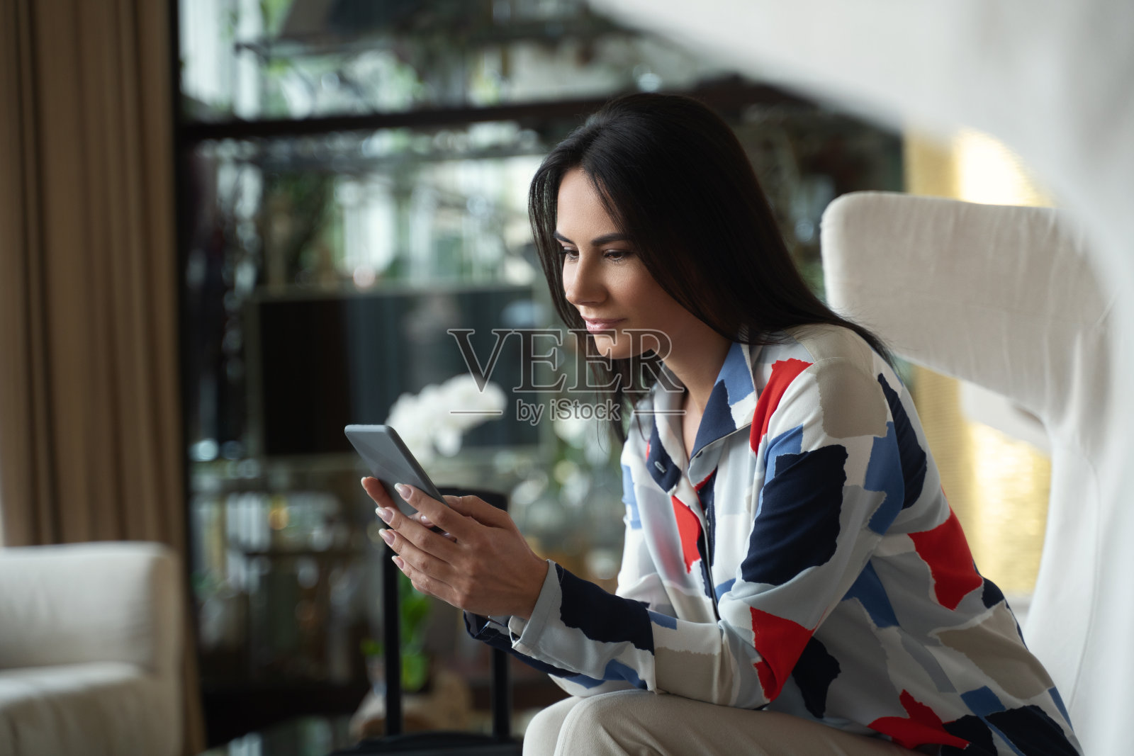聪明可爱的女商人在酒店大厅用手机发短信照片摄影图片