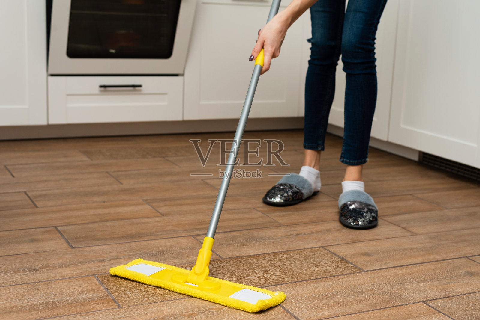 一位妇女在她的房子里清洗地暖。管家手里的拖把照片摄影图片