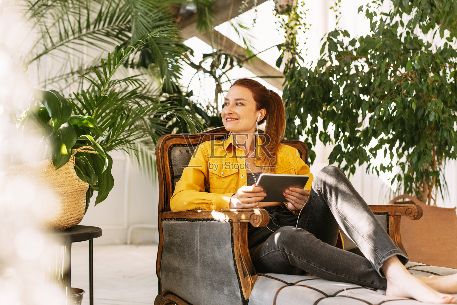 近距离肖像美丽的女人坐在花园里，而持有数字平板电脑。年轻有魅力的快乐女人是用平板电脑带着笑脸，网上购物的概念照片摄影图片