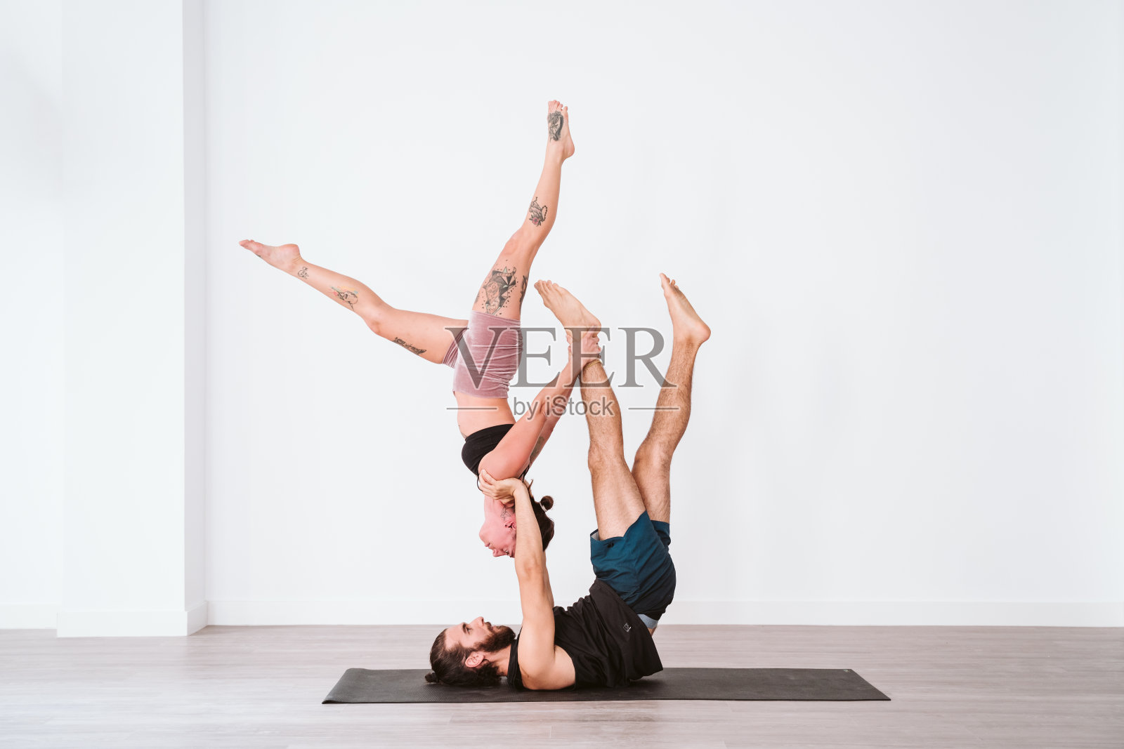 年轻夫妇在白色的工作室或健身房练习瑜伽。健康的生活方式照片摄影图片
