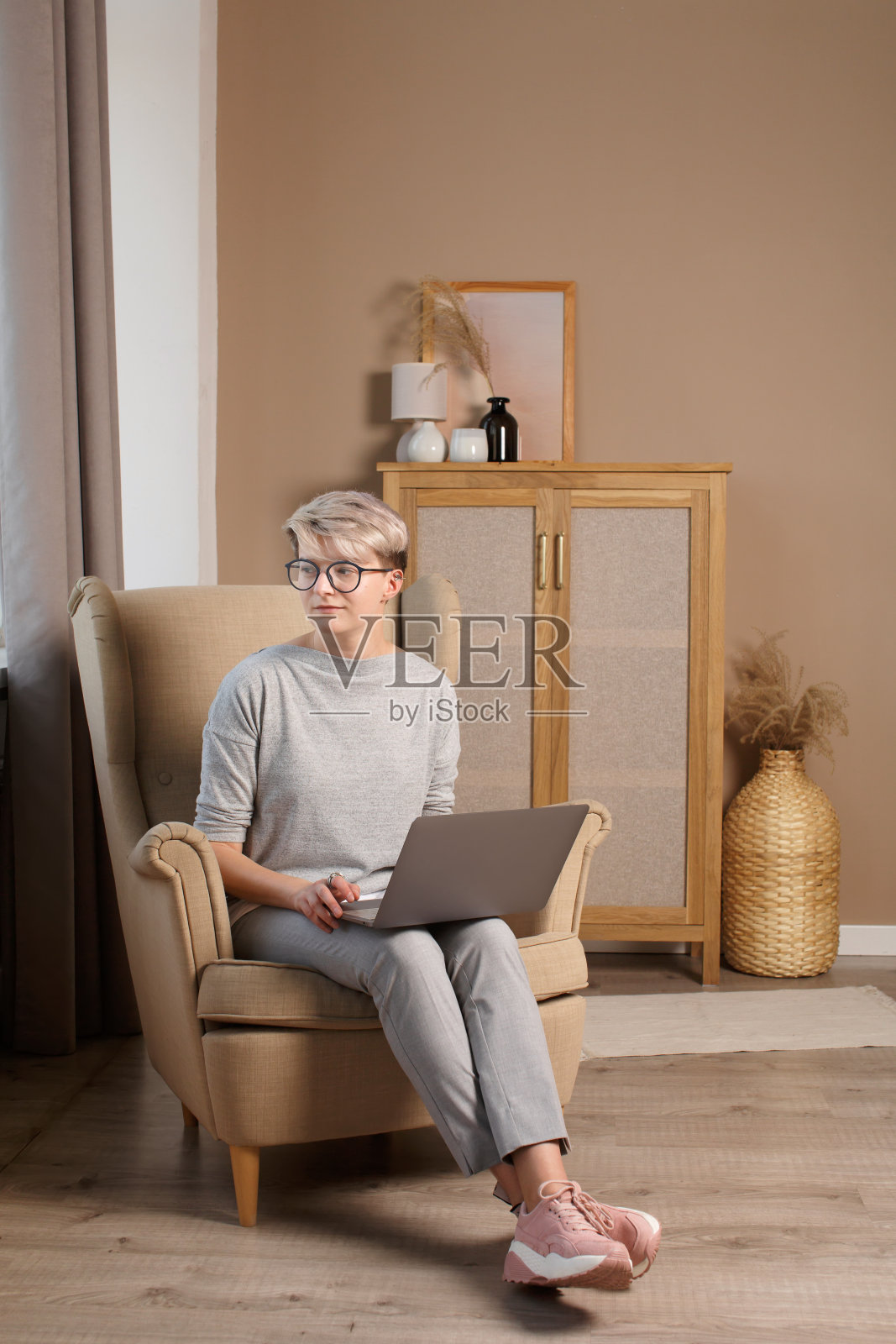 全身像漂亮聪明的女孩在休闲衣服上写在笔记本电脑看窗户。照片摄影图片