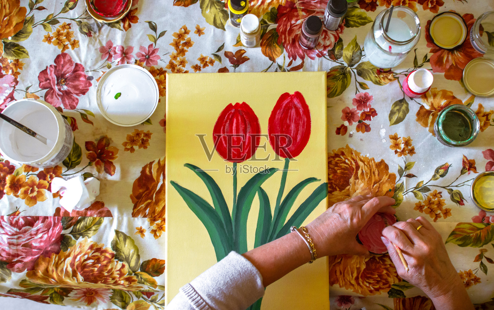 俯视图，一个女人的手在家里和桌子上画满了材料。在家画画。照片摄影图片