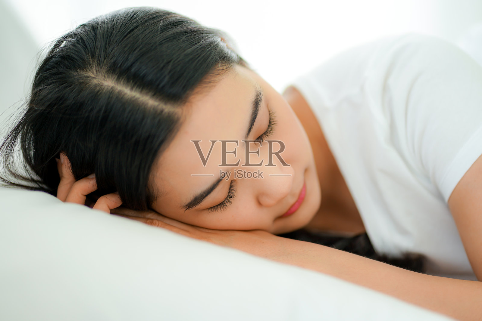 年轻的亚洲女子躺在床下的干净的白色被子在假日工作期间从家里社交距离照片摄影图片