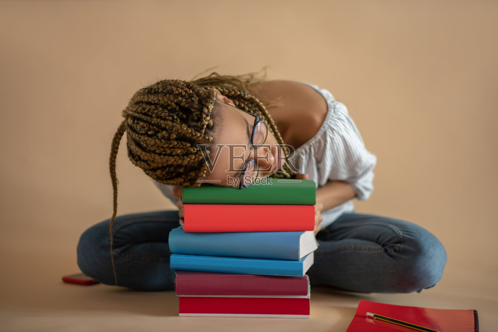 疲惫的年轻非洲裔美国女性戴着眼镜睡在一堆书照片摄影图片