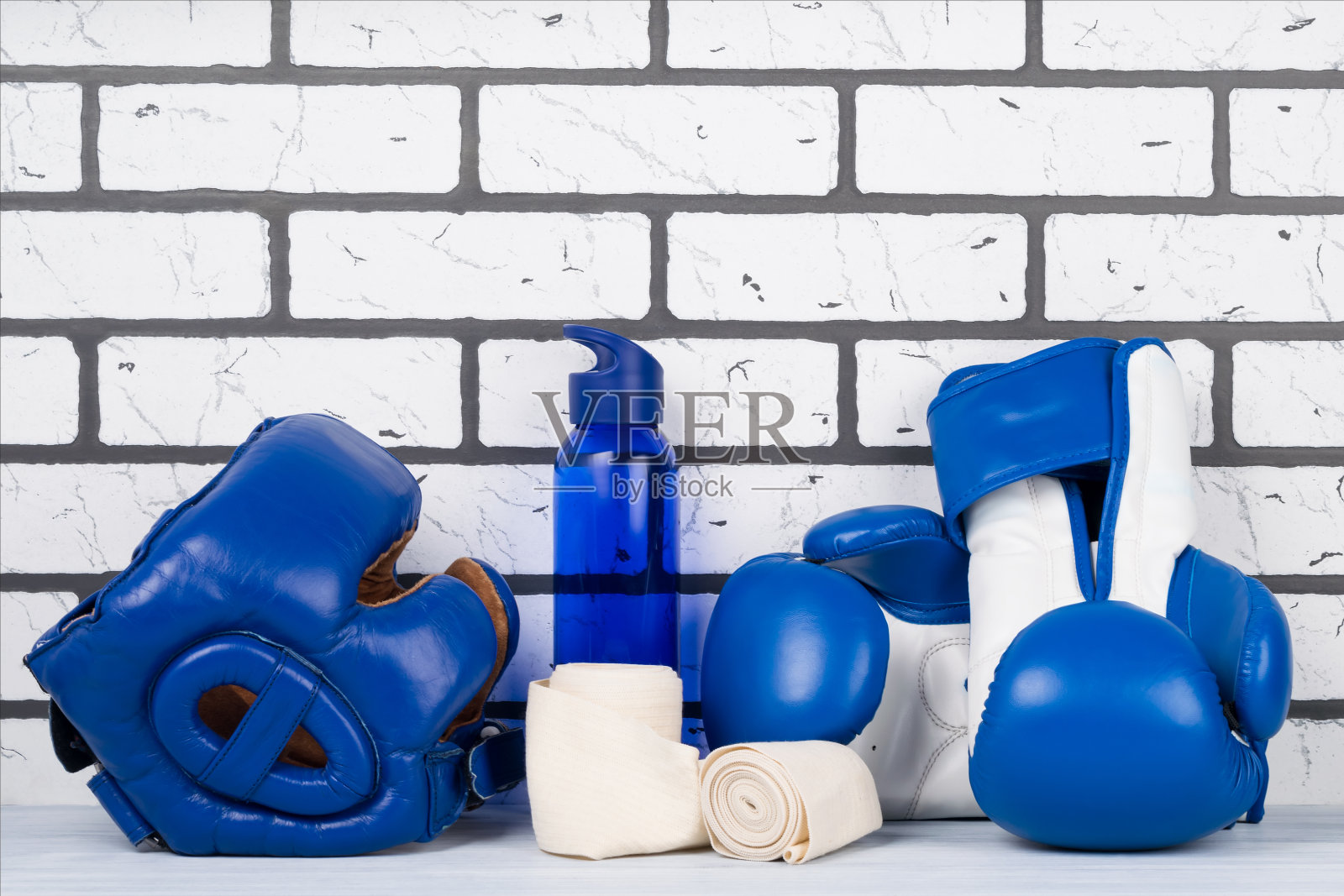 砖墙背景上的蓝色头盔和拳击手套照片摄影图片