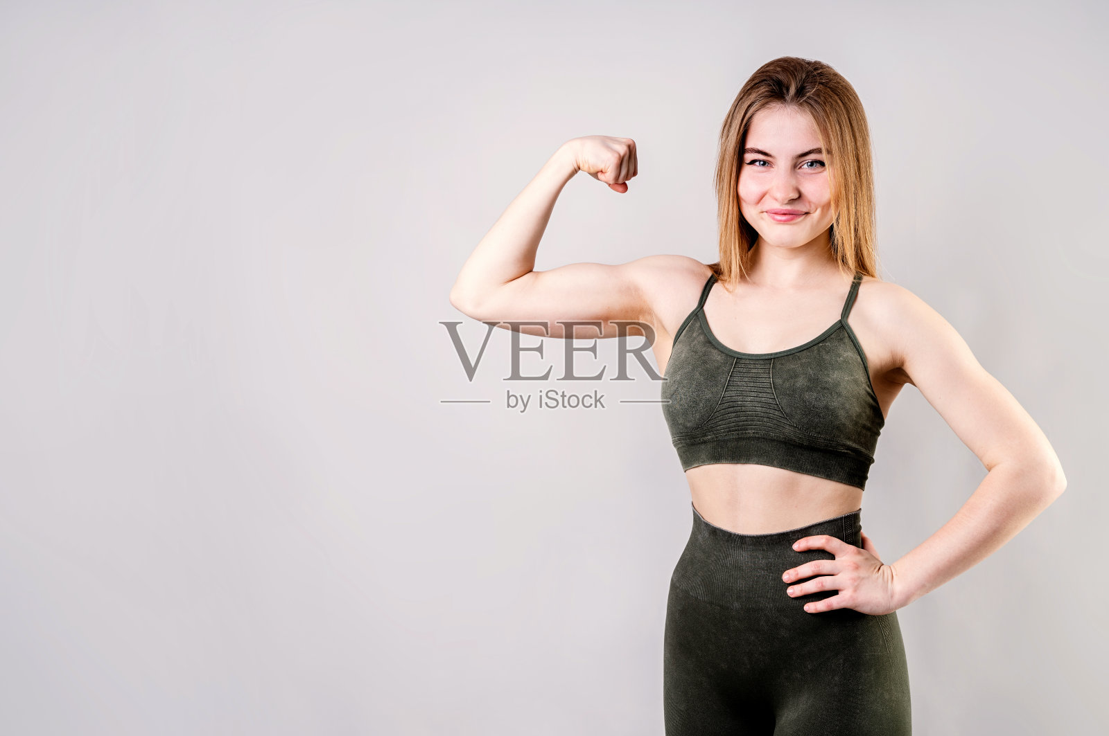 运动微笑的女人展示二头肌孤立在灰色背景照片摄影图片
